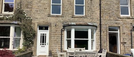 A stone building with a number 3 door, a bay window, and a small porch with a bench.