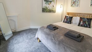 Une chambre à coucher comprenant un lit, une tête de lit, une table de chevet, une lampe et des œuvres d’art murales.