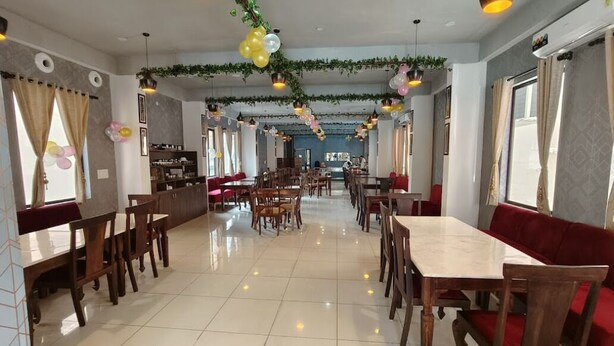 Un grand espace dédié à la salle à manger, avec plusieurs tables et chaises, un coin cuisine et une vue sur la ville.