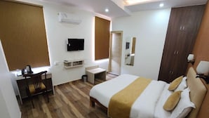 Une chambre d’hôtel équipée d’un lit, d’un bureau, d’une télévision et d’un ventilateur de plafond.