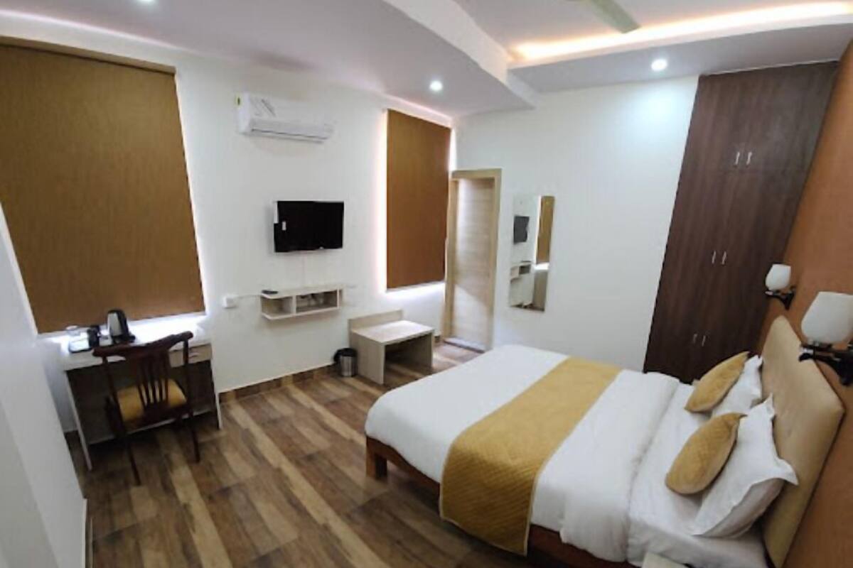 Una habitación de hotel con cama, escritorio, televisor y ventilador de techo.