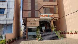 Un hôtel à la façade moderne, avec un escalier menant à l’entrée et une enseigne « PAPRIKA » au-dessus de la porte.