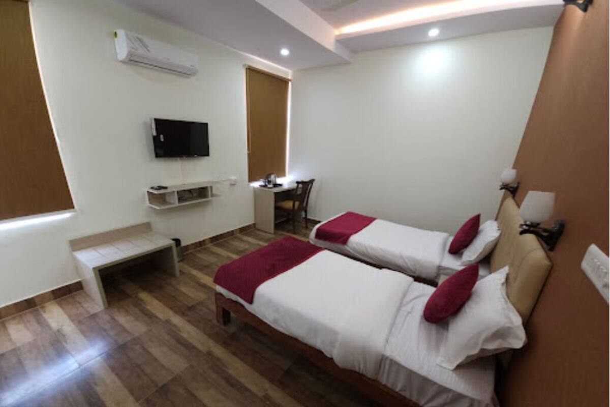 Una habitación de hotel con dos camas, televisión, escritorio y silla.