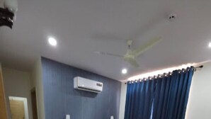 Une chambre d’hôtel équipée d’un lit, d’un bureau, d’une chaise, d’un ventilateur de plafond et d’un appareil de climatisation.
