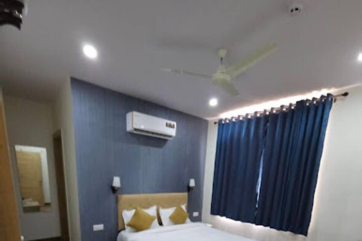 Habitación de hotel con cama, escritorio, silla, ventilador de techo y aire acondicionado.