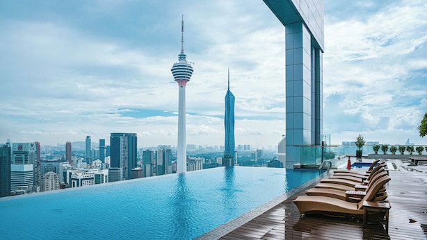Una piscina infinita con vista al horizonte de la ciudad, que incluye una torre y edificios modernos.