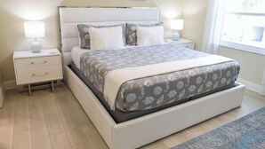 A bedroom with a bed, nightstands, and a window.