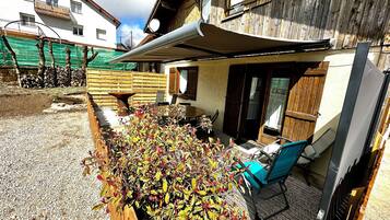 A residential property with a covered patio, outdoor seating, and a garden area.