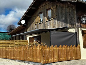 Een landelijk houten gebouw met een overdekte patio, een houten omheining en een bordje met de naam Dryade restaurant.