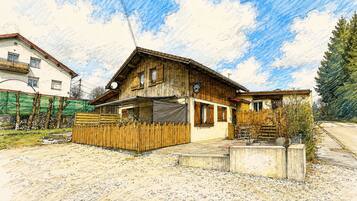Ein Holzhaus mit Satteldach, einem umzäunten Garten und einem gepflasterten Auffahrt.