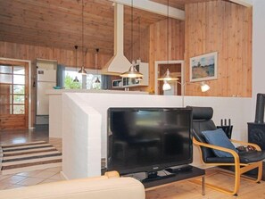 Relax in this stylish living space with a large flat-screen TV, comfortable sofa, and fully equipped kitchen area.