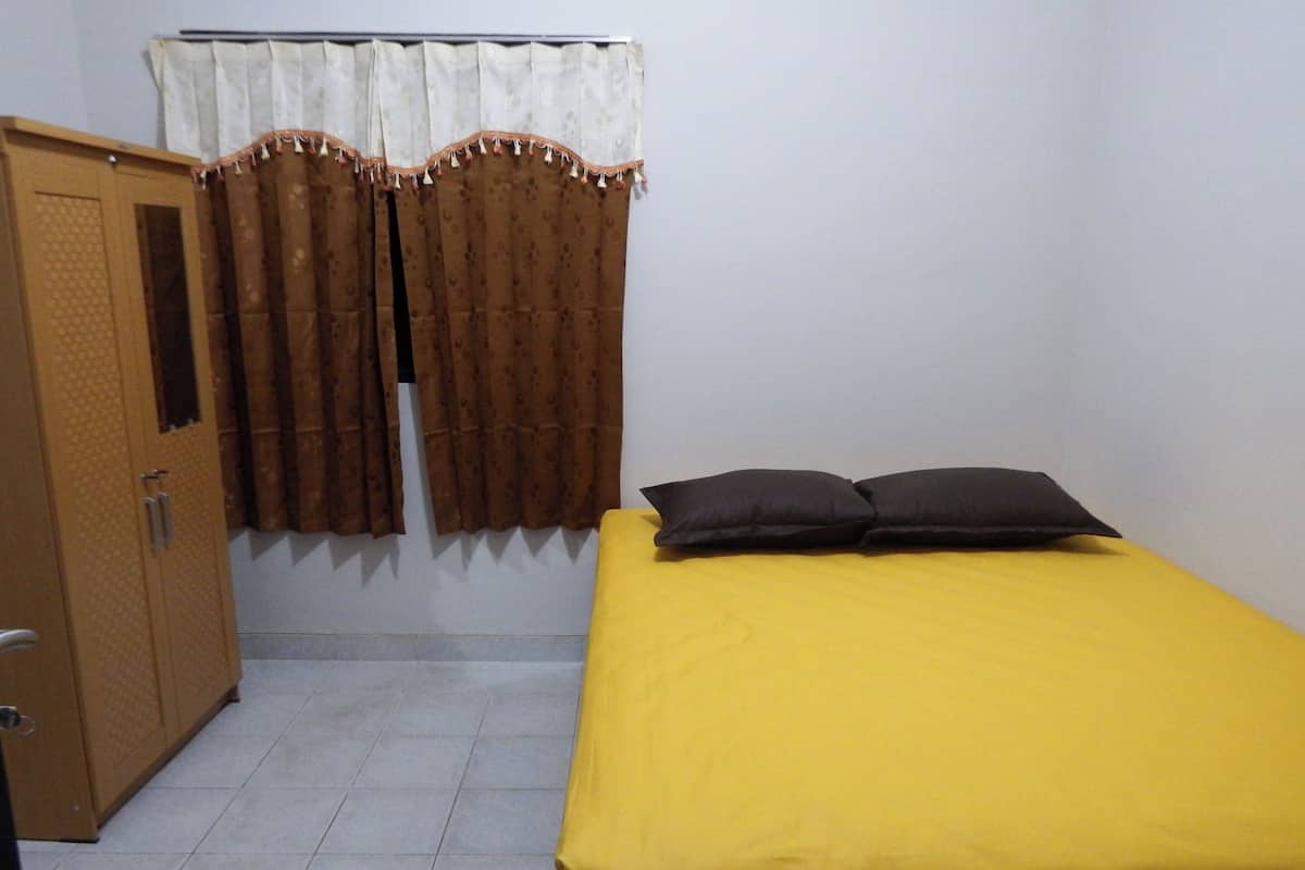 A small room with a bed, a wardrobe, and curtains.
