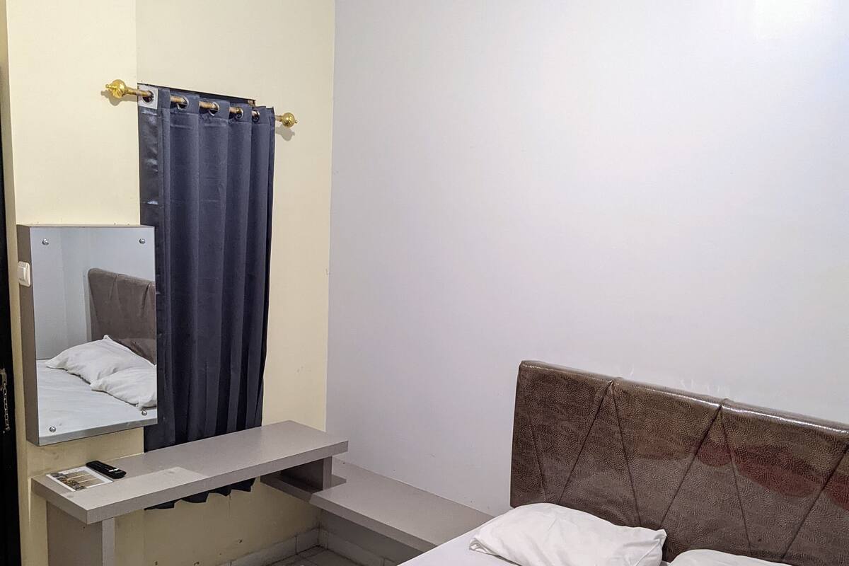 Una habitación de hotel con cama, escritorio y espejo.