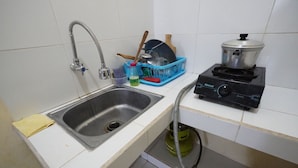 Una cocina con un lavamanos de acero inoxidable, una estufa a gas y un escurreplatos azul.