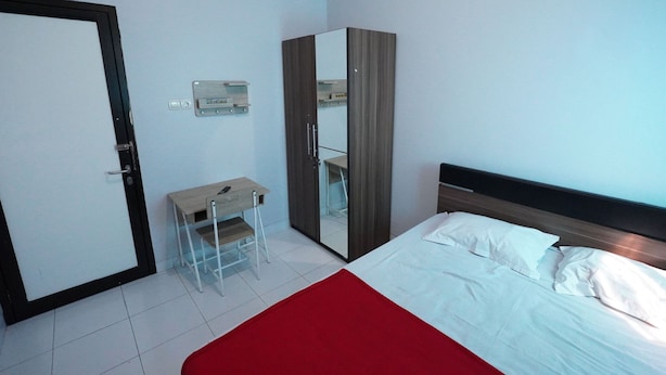 Un dormitorio con cama, escritorio, armario y puerta.