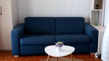 A living room with a blue sofa, a white coffee table, and a woven rug.