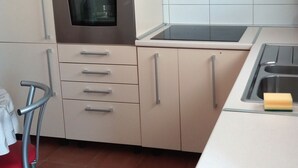 Een keuken met een inbouwoven, een roestvrijstalen spoelbak en een afzuigkap.