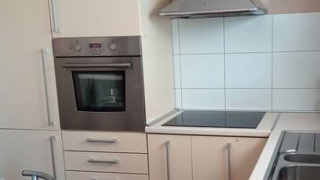 A kitchen with a built-in oven, a stainless steel sink, and a ventilation hood.
