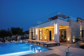 Une villa moderne dotée d’une piscine, d’un espace extérieur aménagé et de murs en pierre.