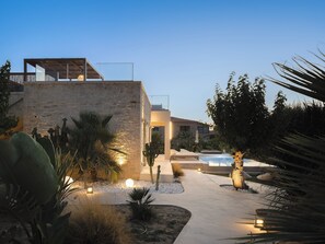 A modern outdoor area with a pool, stone walls, and various plants.
