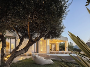 A modern outdoor seating area with a tree, a stone wall, and a pool.