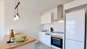 Eine moderne Küche mit weißen Schränken, einem Edelstahlkühlschrank, einem eingebauten Ofen und einer Holzarbeitsplatte.