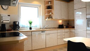 A modern kitchen with a dishwasher, a coffee maker, and a window with a view.