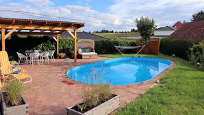A backyard with a swimming pool, patio furniture, and a pergola.
