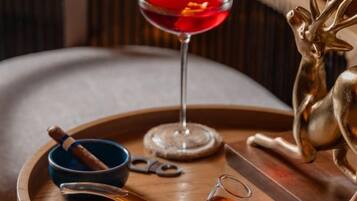 A tray with a martini glass, a small bowl with a cinnamon stick, a pair of scissors, and a bottle of whiskey.