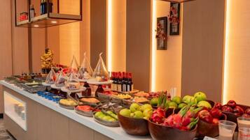 A buffet with various food items and beverages, including fruits, vegetables, and drinks.