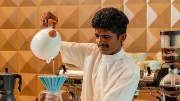A person pouring liquid from a jug into a coffee maker.