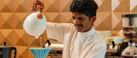 A person pouring liquid from a jug into a coffee maker.