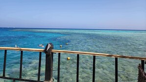 A clear view of the ocean from a wooden balcony with a metal railing. - Chalet Stella Makadi Beach 5 Stars (Makadi Bay)