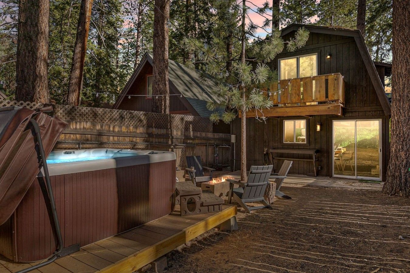 A cabin with a hot tub, outdoor seating, and a deck.