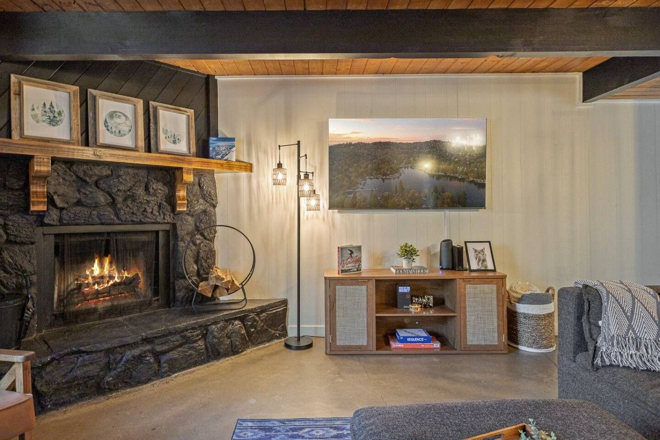 Ein gemütliches Wohnzimmer mit Kamin aus Stein, einem großen Gemälde und einer Bücherwand.