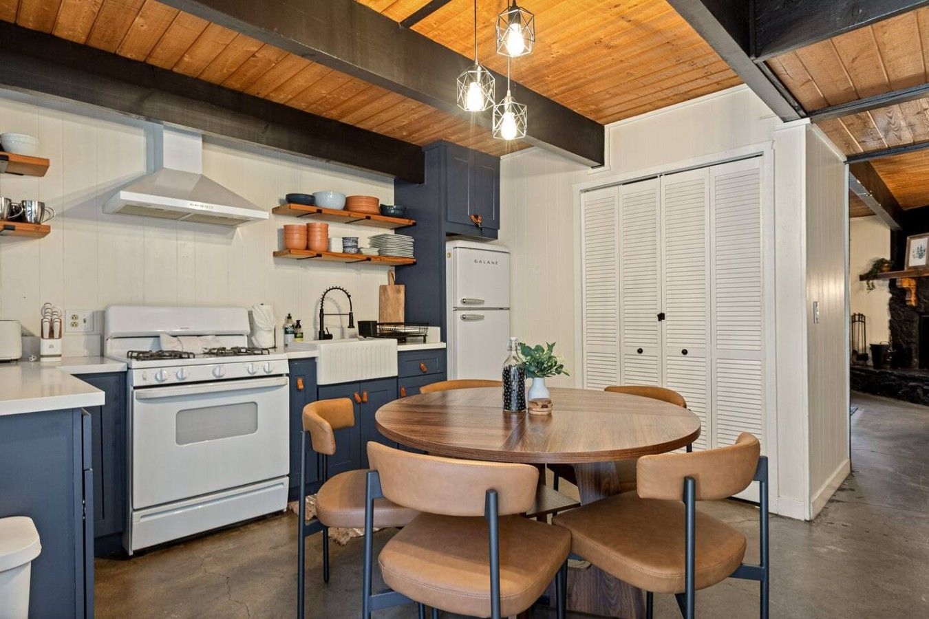 Une cuisine moderne dotée d’un îlot central, d’appareils électroménagers blancs et d’un coin repas avec une table ronde et des chaises.