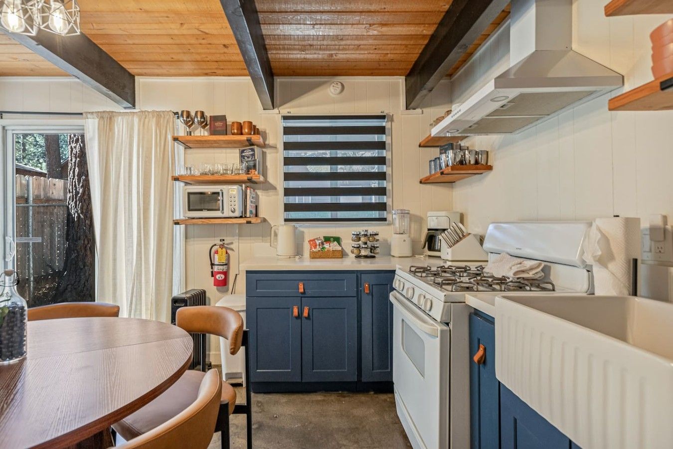 A compact kitchen with a gas stove, microwave, and blue cabinets.