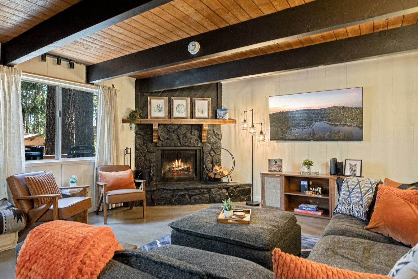 A cozy living room with a fireplace, comfortable seating, and a large window.