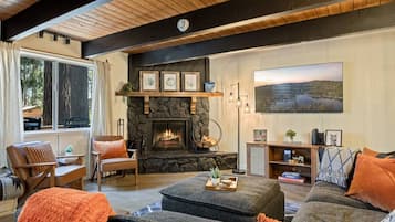 A cozy living room with a fireplace, comfortable seating, and a large window.