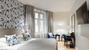 A modern hotel room with a large bed, a desk, a chair, and a TV mounted on the wall. - Hotel Bastian  (Helsinki)