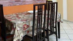 A dining area with a table set for four, chairs, a stone accent wall, and a framed artwork above the table. - Tns Apartment Durres (Golem)
