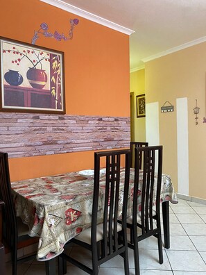 A dining area with a table set for four, chairs, a stone accent wall, and a framed artwork above the table.