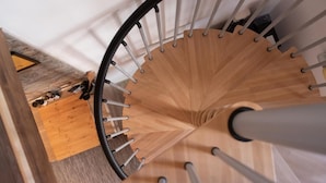 Un escalier en colimaçon avec des marches en bois et des balustrades en métal.