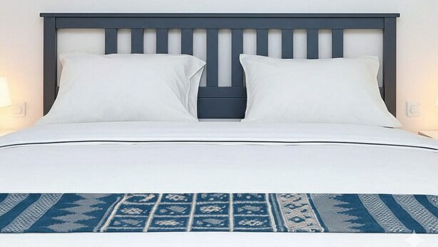 A bed with a dark headboard, white pillows, and a blue patterned bedspread. - Seaside Bliss Getaway (Al-Manasrah)