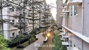 Un immeuble résidentiel doté de nombreux balcons, d’un chemin central et entouré de verdure.