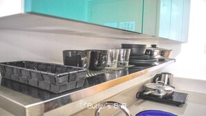 Un comptoir de cuisine avec un plateau noir, plusieurs verres, une casserole et une bouilloire.