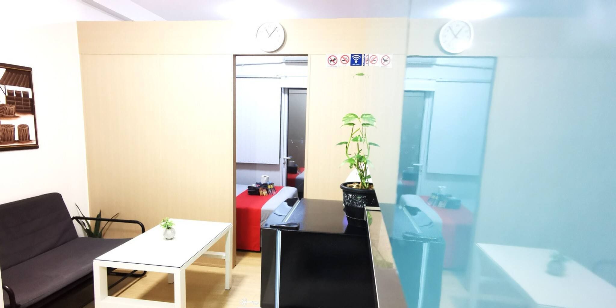 Une pièce avec une table blanche, un canapé noir, une table rouge et une plante en pot.