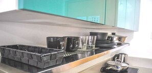Un comptoir de cuisine avec un plateau noir, plusieurs verres, une casserole et une bouilloire.