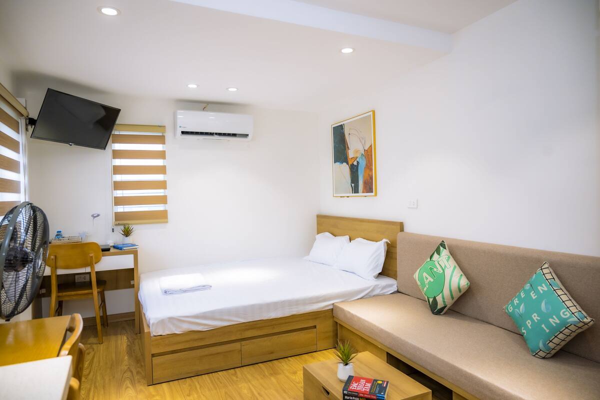 Une chambre d’hôtel de taille réduite, comprenant un lit, un canapé, un bureau et un téléviseur.