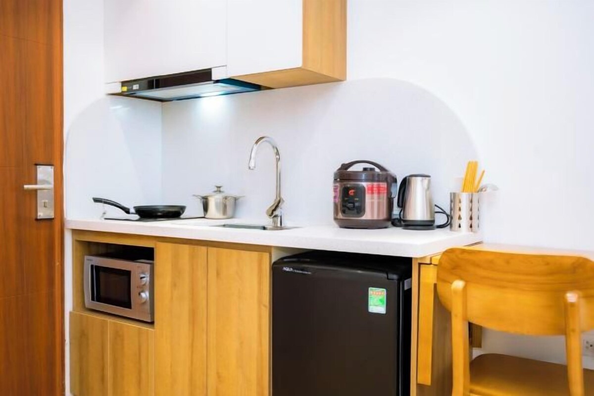 A compact kitchen with a microwave, a black refrigerator, a kettle, and a coffee maker on the counter.